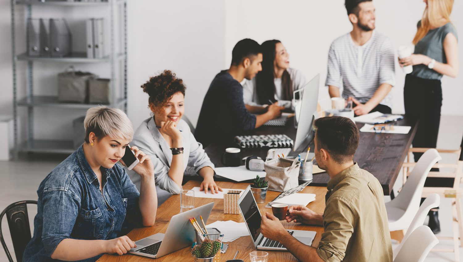 Friends and coworkers wearing casual clothes, working together at open space in marketing agency
